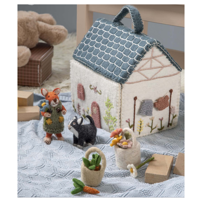 A felted wool house with a blue roof, designed for imaginative play. The house is open, revealing a charming interior with embroidered details.