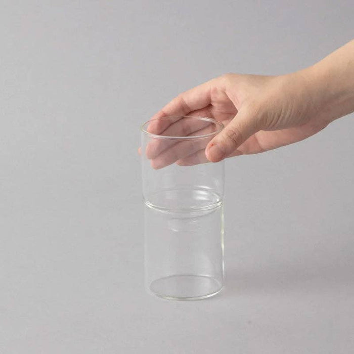 Clear glass vae held by a hand on a gray background