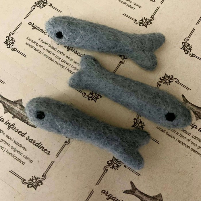 Three gray felted fish toys on a textured paper background with text.