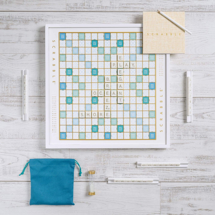 Scrabble board game set on a wooden surface with tiles and bags.
