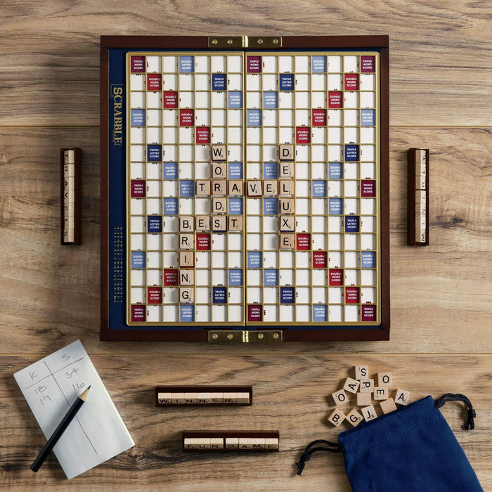 Scrabble board game on a wooden surface with tiles and components.