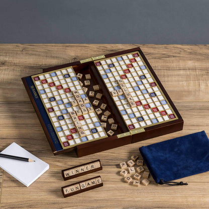 Travel Scrabble game board unfolded and open on a wooden table with tiles and pieces.