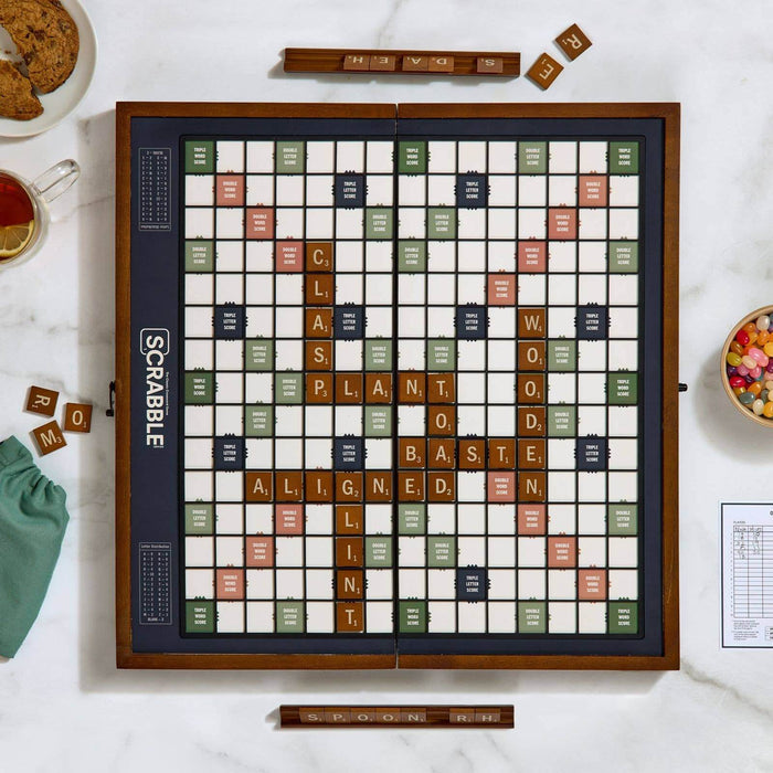 Scrabble board game on a table with tiles and food.