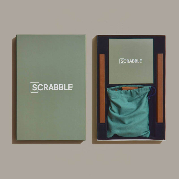 Scrabble game set with green bag and packaging on a beige background